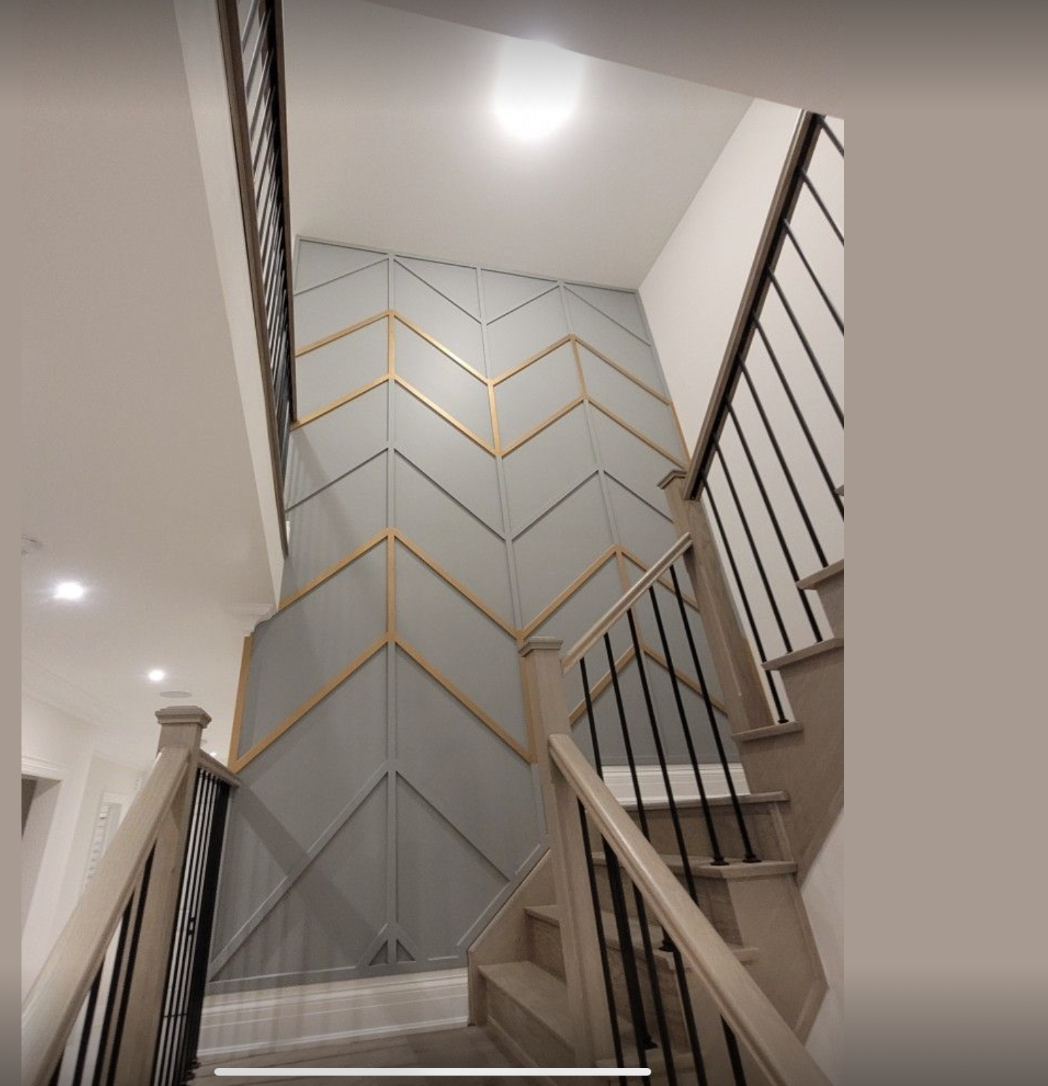 Treppenhauswand mit Chevron-Muster und goldenen Holzleisten Bessungen