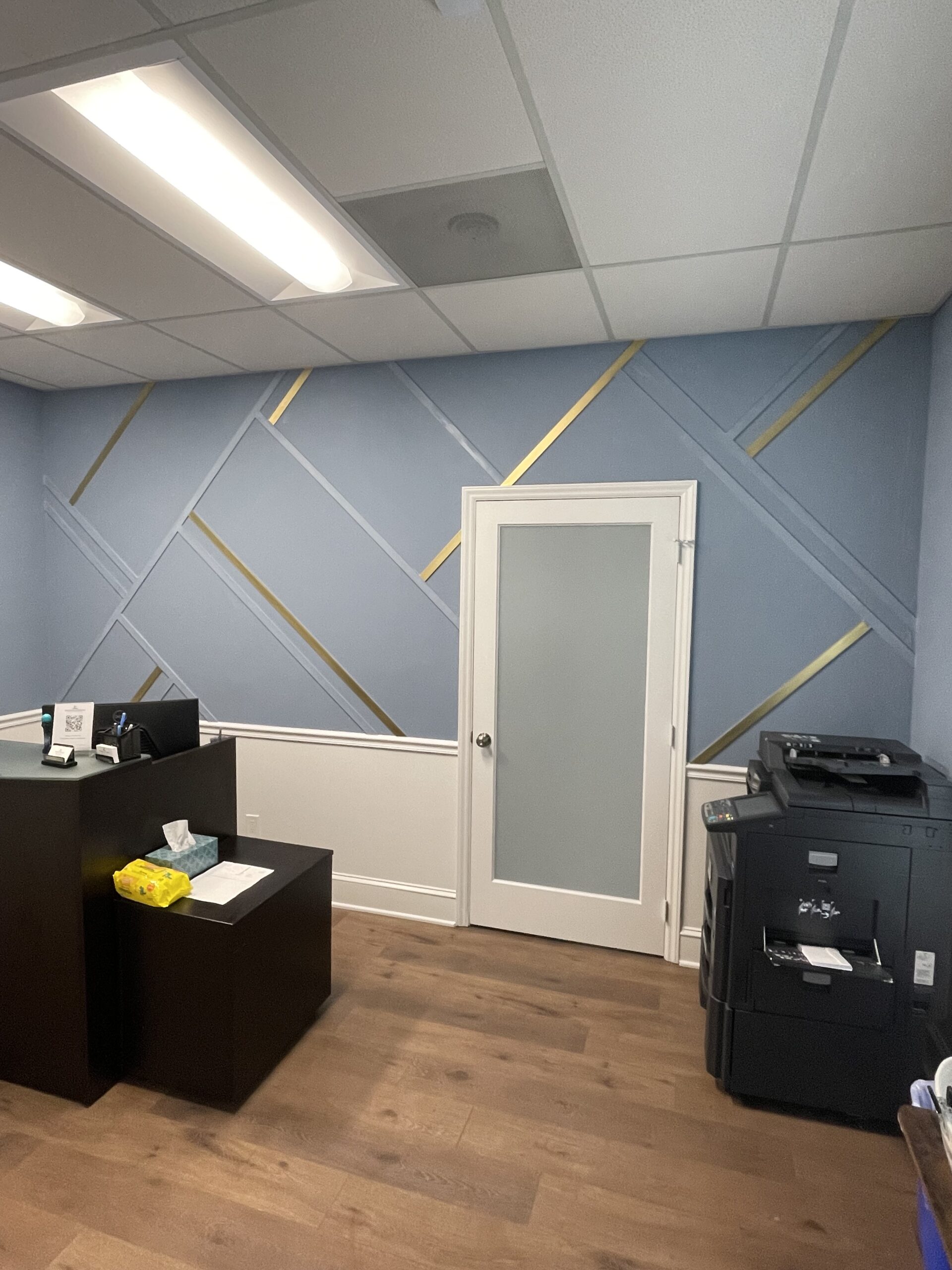 Geometrische Wandgestaltung mit goldenen Zierleisten in Büro