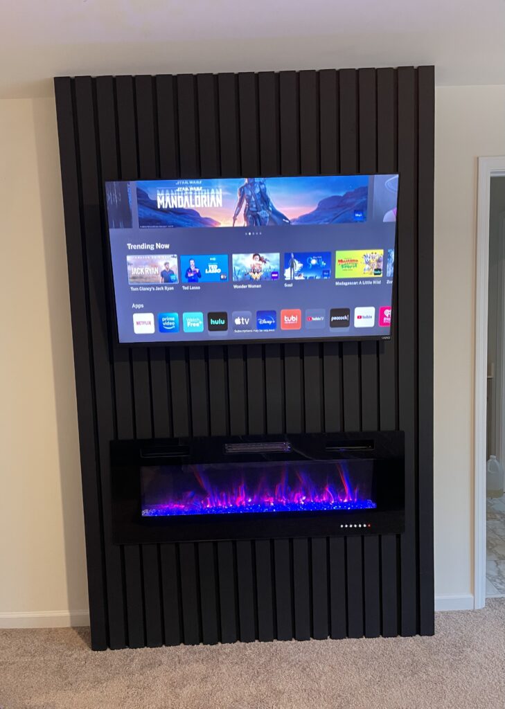 Moderne Medienwand mit blauem Elektrokamin und integriertem Fernseher – umgesetzt von Majetic Raum & Ausbau